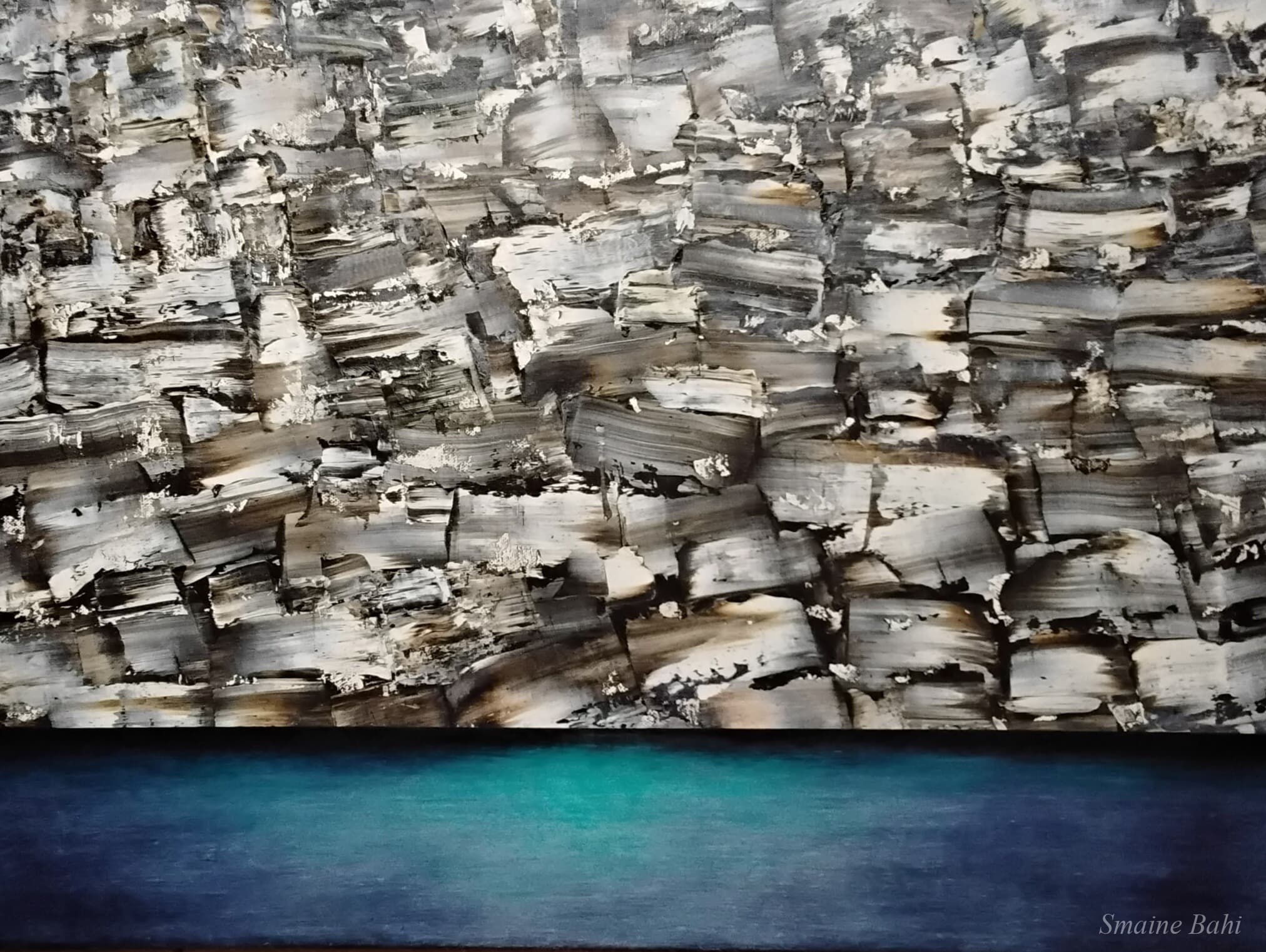 Iridium – Ölgemälde 93 × 68 cm von Smaine Bahi, pastos gespachtelte silbrig-graue Felsenwand über tief türkisblauer, spiegelglatter Wasserfläche
